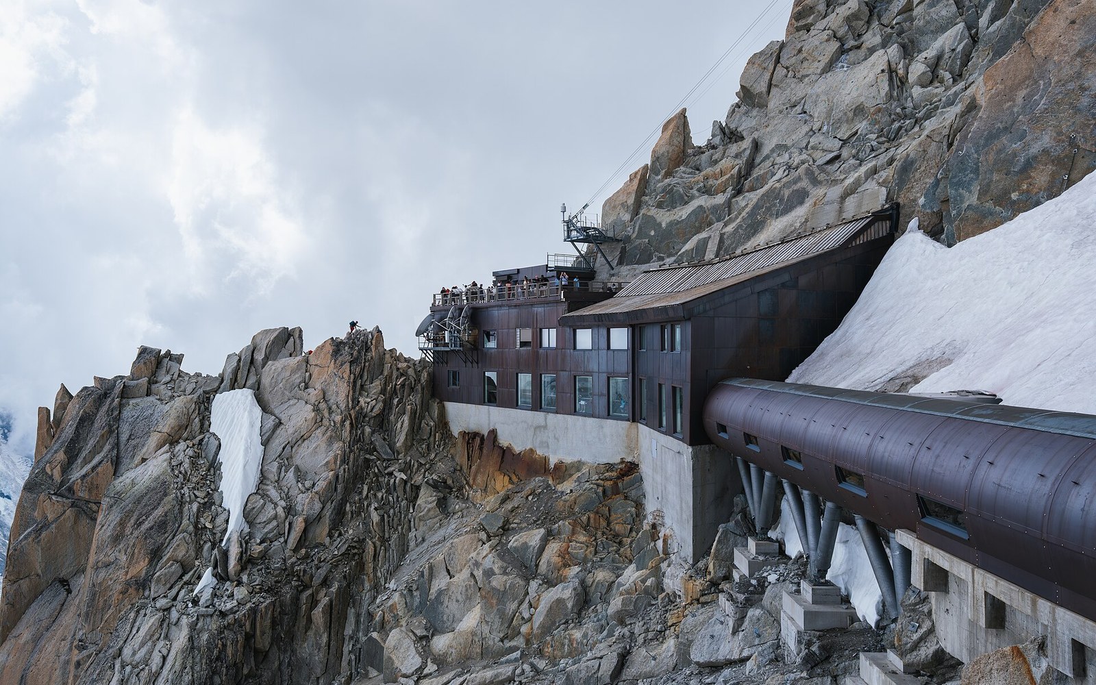 The Aiguille du Midi summit station on its rock pinnacle against a blue-black sky, the cable visible below
