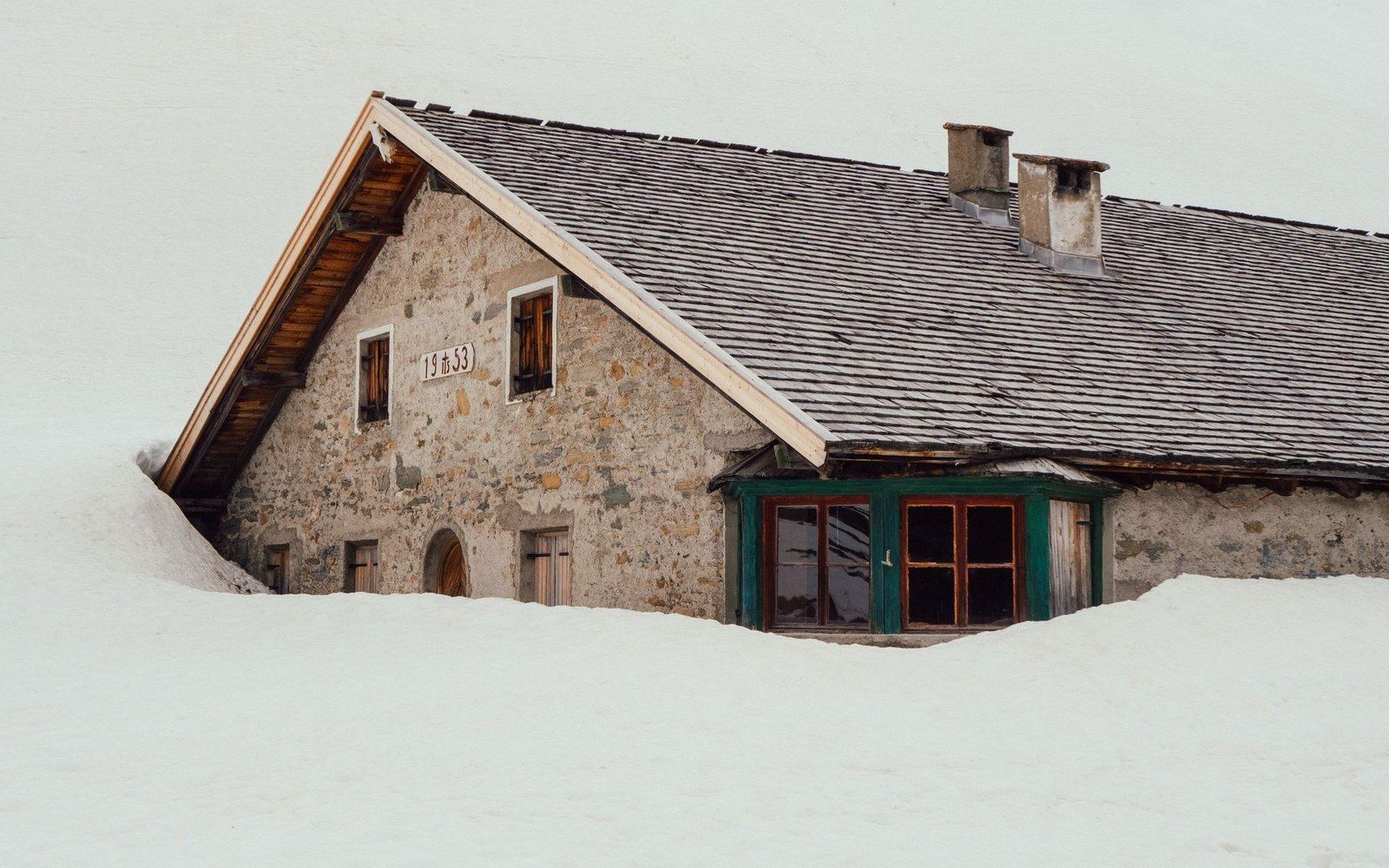 A lauze-roofed stone chalet in Albiez-Montrond with the Maurienne valley visible behind it in morning light