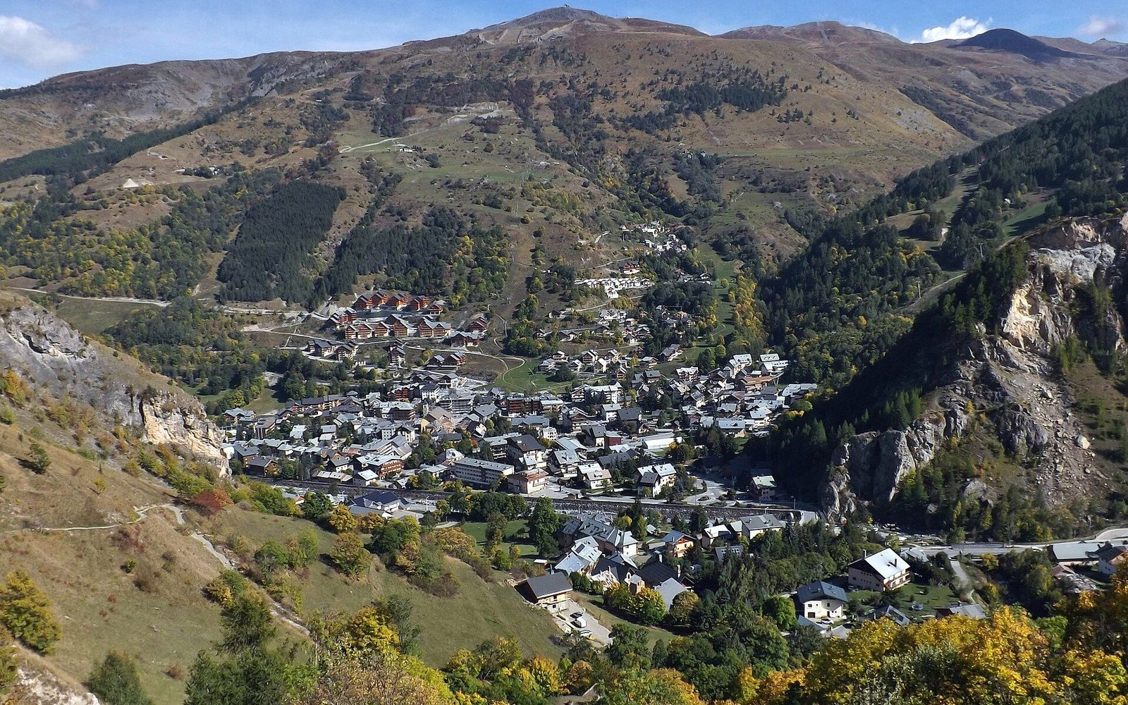 Valloire's rooftops cluster in a valley surrounded by steep, forested alpine slopes